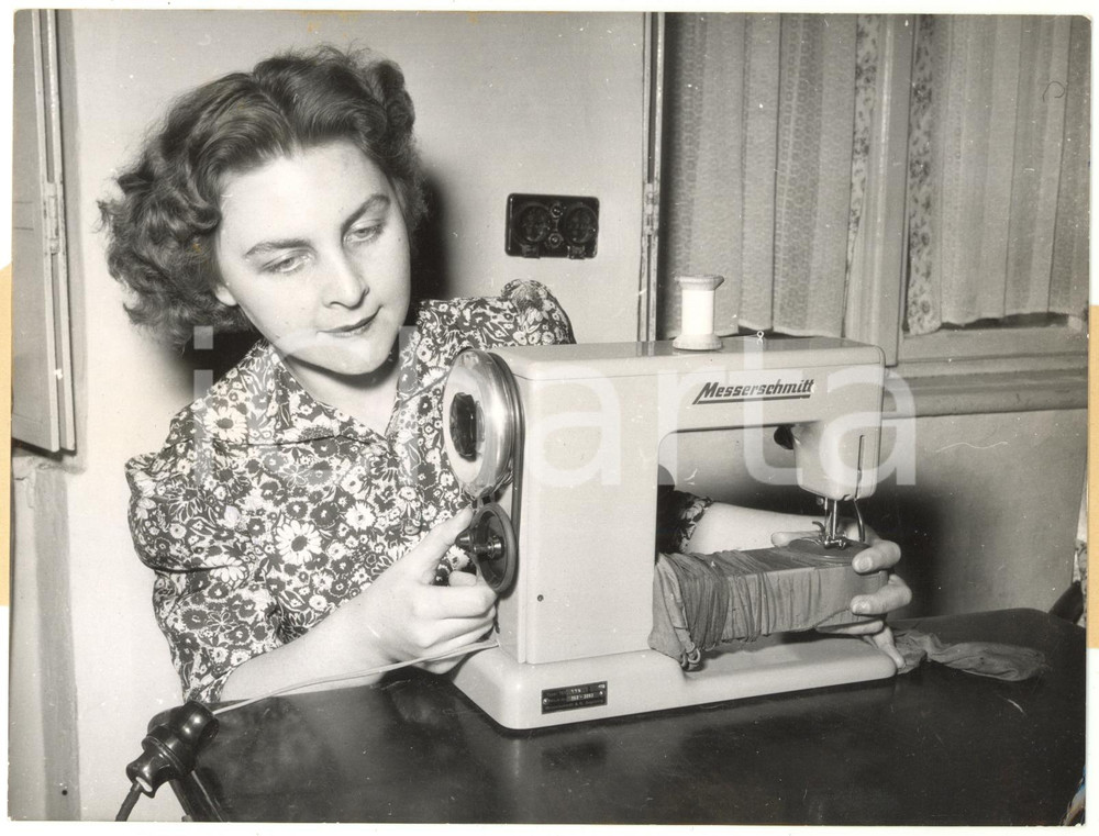 1953 GERMANY Housewife using the new electric sewing-machine MESSERSCHMITT Photo Fotografia d'epoca, con didascalia coeva al verso. CONDIZIONI: FAIR (sovraimpressione circolare al lato inferiore, piegatura all'angolo inferiore destro, difetti di stampa, minima increspatura al margine sinistro e minime bruniture al margine superiore)FORMATO: 20x15 cm    originale e autentica 1