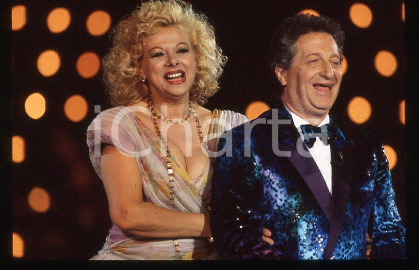 Sandra MILO Gianfranco D'ANGELO *Raffaella Carrà Show 1988 *35mm vintage slide 1 Diapositiva d'epoca, in formato 35 mm. E' severamente vietata la riproduzione. Tutti i diritti sono riservati.  ICharta mette in vendita, sul negozio eBay e in esclusiva sul sito "icharta" il proprio archivio composto da numerose diapositive e negativi fotografici d'epoca, tutti originali e autentici, che attraversano la storia del costume tra la fine degli anni Sessanta e Novanta.Si tratta di uno sguardo inedito sull'attualit&agrave;, la politica, la vita quotidiana, il gossip e la cultura, che fotografa il cambiamento della nazione in quest'ultimo scorcio del XX secolo. Un'occasione unica per il mercato del collezionismo, che vede finalmente disponibile un archivio eccezionale per vastit&agrave;, tematiche e condizioni, in un settore (il negativo fotografico e la diapositiva) di assoluta novit&agrave; e dalle interessanti prospettive di investimento.  GOOD/buono   originale e autentica 1