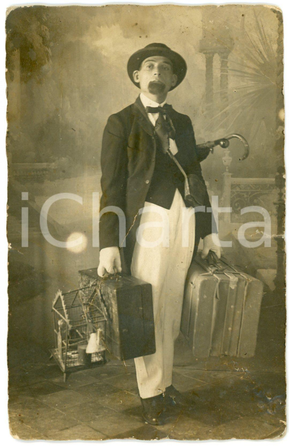 1920 ca ITALIA Ritratto di giovane con valigie e gabbietta *Foto CURIOSA 9x14 cm  Fotografia d'epoca, in formato cartolina postale.CONDIZIONI: VP (piegature diffuse; bruniture al verso; piccolo strappo al lato destro)FORMATO: 9x14 cm    originale e autentica 1