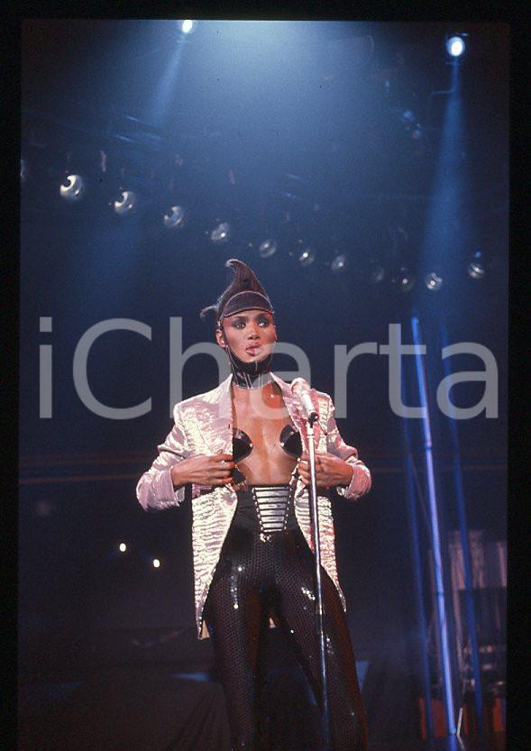1985 ca MUSICA Grace JONES durante un concerto * 35 mm vintage slide (63) Diapositiva d'epoca, in formato 35 mm.CONDIZIONI: GOODE' severamente vietata la riproduzione. Tutti i diritti sono riservati.ICharta mette in vendita, sul negozio eBay e in esclusiva sul sito "icharta" il proprio archivio composto da numerose diapositive e negativi fotografici d'epoca, tutti originali e autentici, che attraversano la storia del costume italiano tra gli la fine degli anni Sessanta e Novanta.Si tratta di uno sguardo inedito sull'attualità , la politica, la vita quotidiana, il gossip e la cultura, che fotografa il cambiamento della nazione in quest'ultimo scorcio del XX secolo. Un'occasione unica per il mercato del collezionismo, che vede finalmente disponibile un archivio eccezionale per vastità , tematiche e condizioni, in un settore (il negativo fotografico e la diapositiva) di assoluta novità e dalle interessanti prospettive di investimento. GOOD/buono   originale e autentica 1