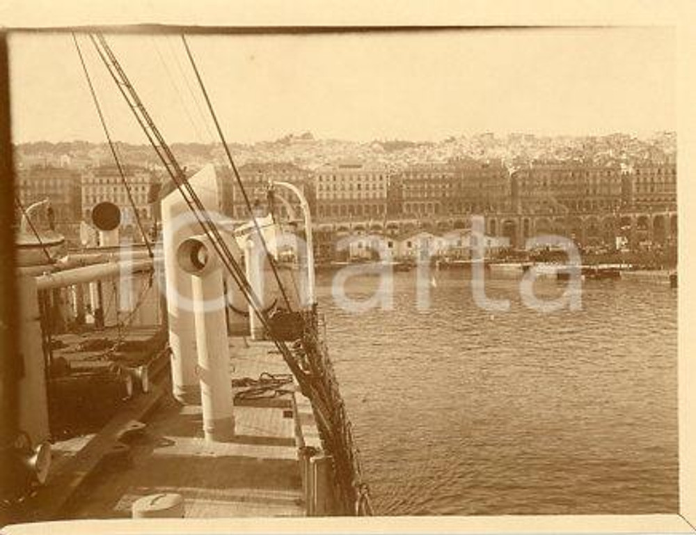 1925 ca ALGERI - Porto e CASBA visti dalla nave (1) - Fotografia 11x9 cm Fotografia originale d'epoca.La fotografia proviene da un più vasto album che documenta i viaggi di una famiglia di nove persone attraverso l'Europa, il Nord Africa e il Sud America.La presente fotografia è stata scattata in Algeria, più precisamente nella zona di Algeri. Rappresenta un'interessante testimonianza di viaggi verso luoghi esotici e lontani o verso i principali monumenti dell'Europa dell'epoca. GOOD/buono minima piegatura angolare Formato: 11x9 cm originale e autentica 1