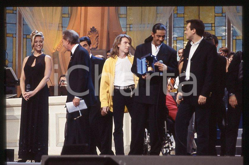 883 FIORELLO Max PEZZALI Festival Italiano 1993 - 35mm vintage slide 12 Diapositiva originale, in formato 35 mm.Scattata durante le riprese della trasmissione televisiva "Festival Italiano".Nella diapositive compare inoltre Mauro Repetto, Mike Bongiorno e Paola Barale.Per i diritti rivolgersi a ICharta.E' severamente vietata la riproduzione. Tutti i diritti sono riservati.ICharta mette in vendita, sul negozio eBay e in esclusiva sul sito "icharta" il proprio archivio composto da numerose diapositive e negativi fotografici d'epoca, tutti originali e autentici, che attraversano la storia del costume tra la fine degli anni Sessanta e Novanta.Si tratta di uno sguardo inedito sull'attualità , la politica, la vita quotidiana, il gossip e la cultura, che fotografa il cambiamento della nazione in quest'ultimo scorcio del XX secolo.Un'occasione unica per il mercato del collezionismo, che vede finalmente disponibile un archivio eccezionale per vastità , tematiche e condizioni, in un settore (il negativo fotografico e la diapositiva) di assoluta novitÃ e dalle interessanti prospettive di investimento. GOOD/buono   originale e autentica 1