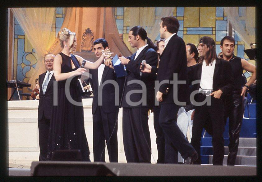 883 FIORELLO Max PEZZALI Festival Italiano 1993 - 35mm vintage slide 17 Diapositiva originale, in formato 35 mm.Scattata durante le riprese della trasmissione televisiva "Festival Italiano".Nella diapositive compare inoltre Mauro Repetto, Mike Bongiorno e Paola Barale.Per i diritti rivolgersi a ICharta.E' severamente vietata la riproduzione. Tutti i diritti sono riservati.ICharta mette in vendita, sul negozio eBay e in esclusiva sul sito "icharta" il proprio archivio composto da numerose diapositive e negativi fotografici d'epoca, tutti originali e autentici, che attraversano la storia del costume tra la fine degli anni Sessanta e Novanta.Si tratta di uno sguardo inedito sull'attualità , la politica, la vita quotidiana, il gossip e la cultura, che fotografa il cambiamento della nazione in quest'ultimo scorcio del XX secolo.Un'occasione unica per il mercato del collezionismo, che vede finalmente disponibile un archivio eccezionale per vastità , tematiche e condizioni, in un settore (il negativo fotografico e la diapositiva) di assoluta novitÃ e dalle interessanti prospettive di investimento. GOOD/buono   originale e autentica 1