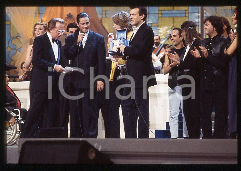883 FIORELLO Max PEZZALI Festival Italiano 1993 - 35mm vintage slide 16 Diapositiva originale, in formato 35 mm.Scattata durante le riprese della trasmissione televisiva "Festival Italiano".Nella diapositive compare inoltre Mauro Repetto, Mike Bongiorno e Paola Barale.Per i diritti rivolgersi a ICharta.E' severamente vietata la riproduzione. Tutti i diritti sono riservati.ICharta mette in vendita, sul negozio eBay e in esclusiva sul sito "icharta" il proprio archivio composto da numerose diapositive e negativi fotografici d'epoca, tutti originali e autentici, che attraversano la storia del costume tra la fine degli anni Sessanta e Novanta.Si tratta di uno sguardo inedito sull'attualità , la politica, la vita quotidiana, il gossip e la cultura, che fotografa il cambiamento della nazione in quest'ultimo scorcio del XX secolo.Un'occasione unica per il mercato del collezionismo, che vede finalmente disponibile un archivio eccezionale per vastità , tematiche e condizioni, in un settore (il negativo fotografico e la diapositiva) di assoluta novitÃ e dalle interessanti prospettive di investimento. GOOD/buono   originale e autentica 1