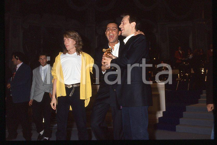 883 FIORELLO Max PEZZALI Festival Italiano 1993 - 35mm vintage slide 20 Diapositiva originale, in formato 35 mm.Scattata durante le riprese della trasmissione televisiva "Festival Italiano".Nella diapositive compare inoltre Mauro Repetto.Per i diritti rivolgersi a ICharta.E' severamente vietata la riproduzione. Tutti i diritti sono riservati.ICharta mette in vendita, sul negozio eBay e in esclusiva sul sito "icharta" il proprio archivio composto da numerose diapositive e negativi fotografici d'epoca, tutti originali e autentici, che attraversano la storia del costume tra la fine degli anni Sessanta e Novanta.Si tratta di uno sguardo inedito sull'attualità , la politica, la vita quotidiana, il gossip e la cultura, che fotografa il cambiamento della nazione in quest'ultimo scorcio del XX secolo.Un'occasione unica per il mercato del collezionismo, che vede finalmente disponibile un archivio eccezionale per vastità , tematiche e condizioni, in un settore (il negativo fotografico e la diapositiva) di assoluta novitÃ e dalle interessanti prospettive di investimento. GOOD/buono   originale e autentica 1