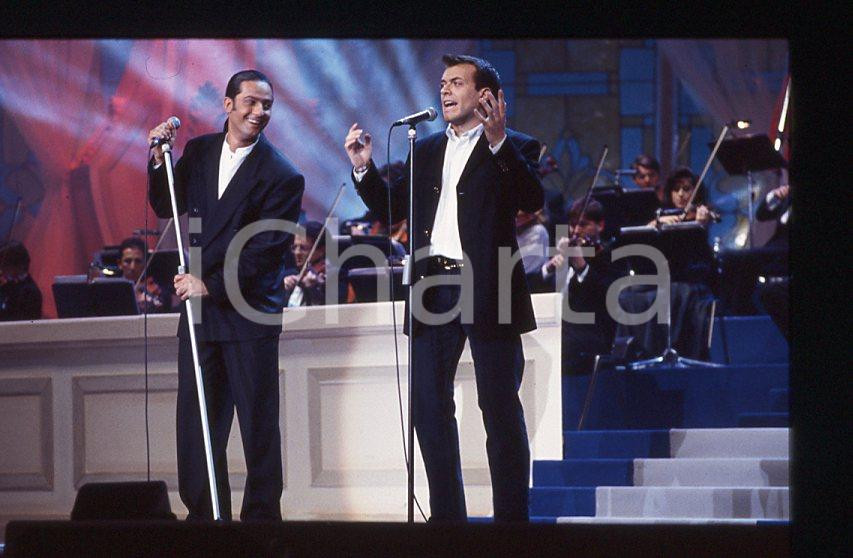 883 FIORELLO Max PEZZALI Festival Italiano 1993 - 35mm vintage slide 29 Diapositiva originale, in formato 35 mm.Scattata durante le riprese della trasmissione televisiva "Festival Italiano".Per i diritti rivolgersi a ICharta.E' severamente vietata la riproduzione. Tutti i diritti sono riservati.ICharta mette in vendita, sul negozio eBay e in esclusiva sul sito "icharta" il proprio archivio composto da numerose diapositive e negativi fotografici d'epoca, tutti originali e autentici, che attraversano la storia del costume tra la fine degli anni Sessanta e Novanta.Si tratta di uno sguardo inedito sull'attualità , la politica, la vita quotidiana, il gossip e la cultura, che fotografa il cambiamento della nazione in quest'ultimo scorcio del XX secolo.Un'occasione unica per il mercato del collezionismo, che vede finalmente disponibile un archivio eccezionale per vastità , tematiche e condizioni, in un settore (il negativo fotografico e la diapositiva) di assoluta novitÃ e dalle interessanti prospettive di investimento. GOOD/buono   originale e autentica 1