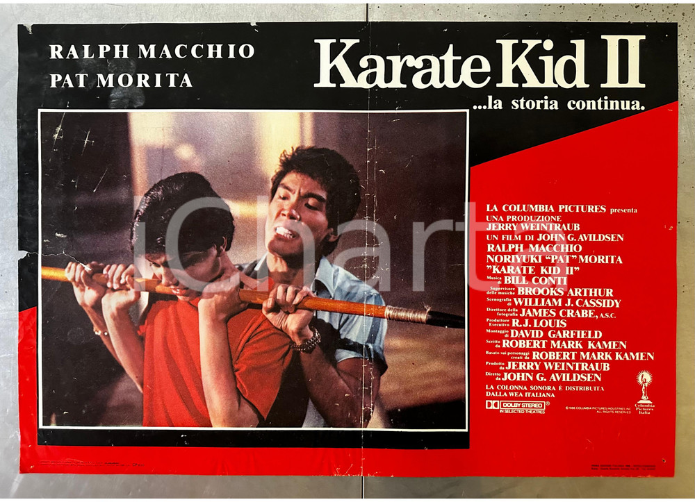 1986 KARATE KID II Ralph MACCHIO Pat MORITA John G. AVILDSEN Lobby card Lobby card d'epoca, originale e autentica.   POOR/danneggiato piegatura centrale, forellini da affissione, piegature ai margni, esteso strappo al margine sinistrohh Formato: 66x46 cm originale e autentica 1