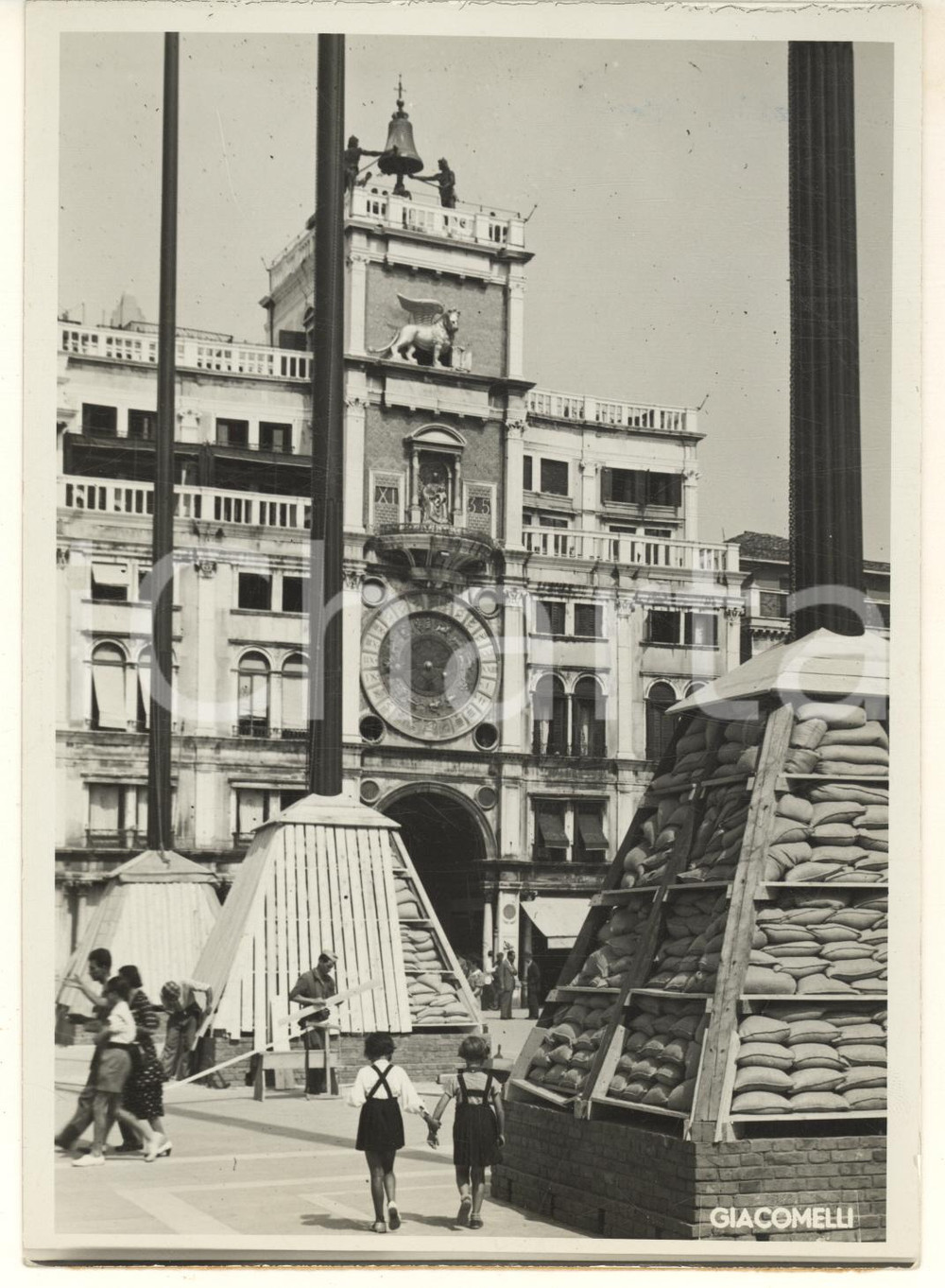 1940 ca WW2 VENEZIA Piazza San Marco - Torre dell'Orologio - Coperture difensive Fotografia originale d'epoca, con didascalia dattiloscritta al verso.Viene mostrata la posa delle protezioni contro i bombardamenti nemici a tutela di piazze e monumenti. FAIR/discreto difetti di stampa, graffi e lievi macchie Formato: 13x18 cm originale e autentica 1