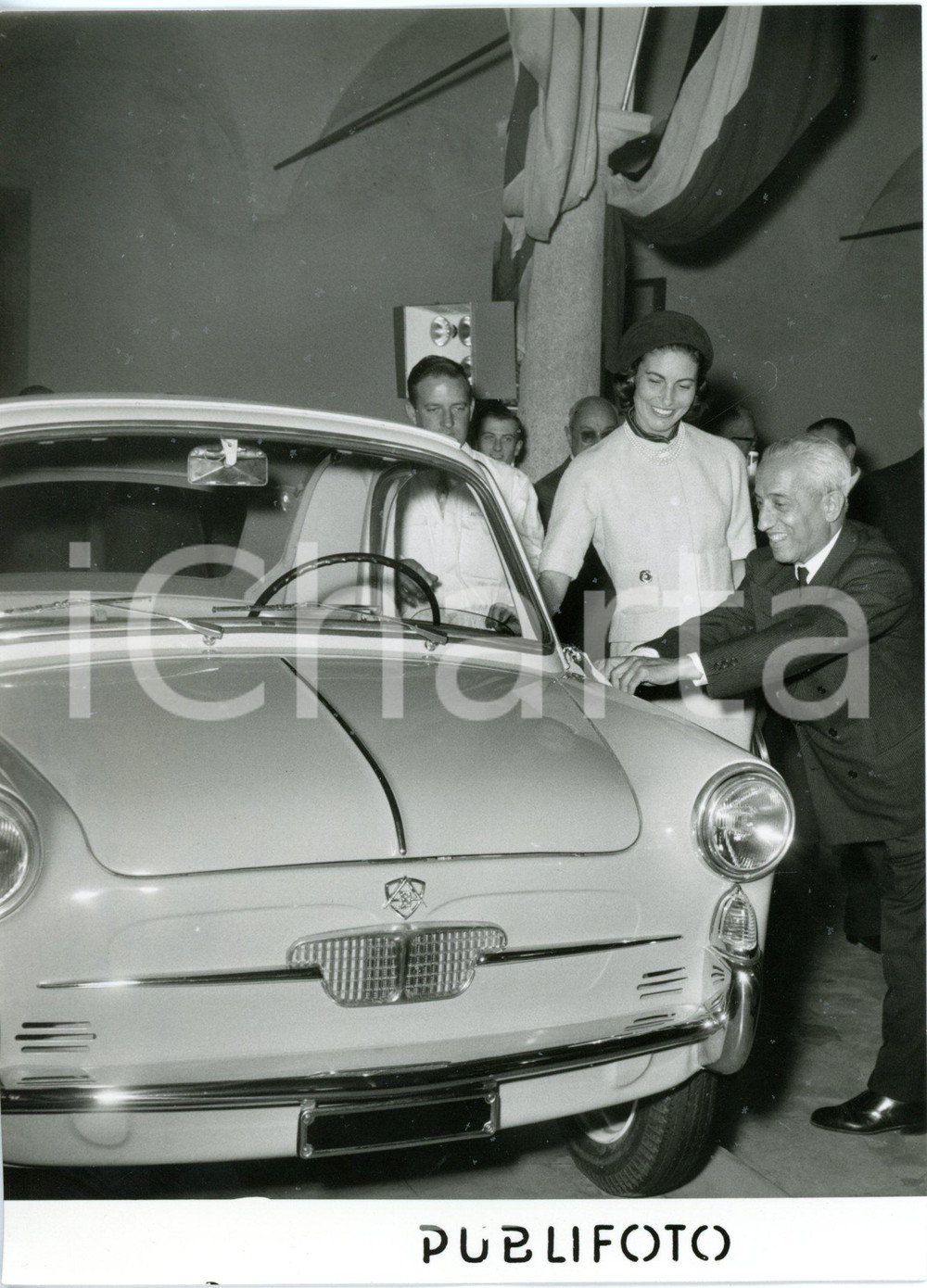 1957 MILANO Vittorio VALLETTA alla presentazione nuova AUTOBIANCHI BIANCHINA  Fotografia d'epoca con didascalia dattiloscritta coeva, scattata presso il Salone della Scienza e della Tecnica di Milano.    CONDIZIONI: G (ma minima increspatura al margine sinistro, lieve sovraimpressione al centro, difetti di stampa) FORMATO: 13x18 cm     originale e autentica 1