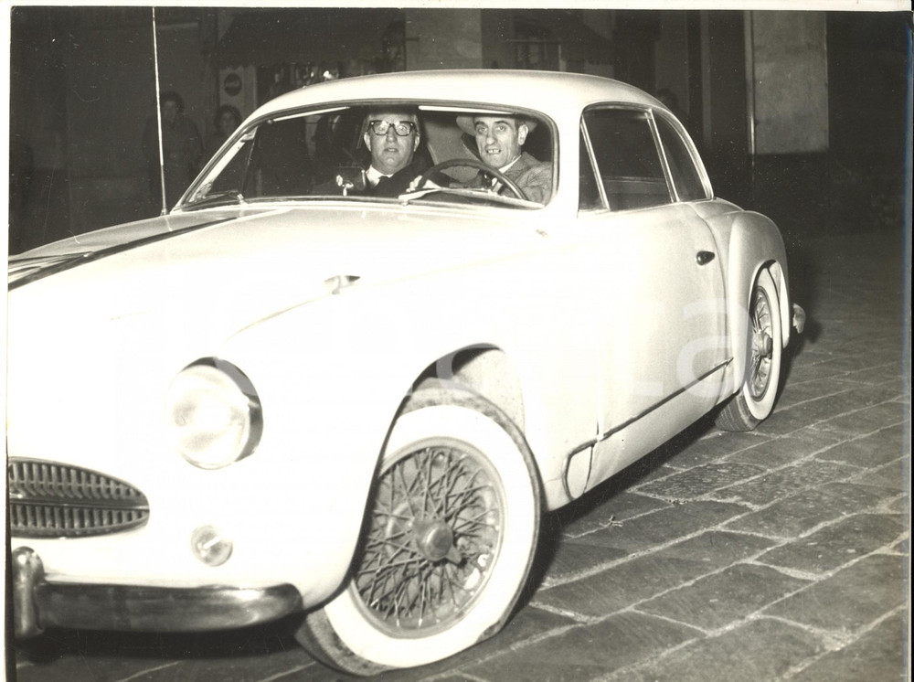 1959 GENOVA Piazza Fossatello - Mario CAROTENUTO in ALFA ROMEO con gomma a terra Fotografia d'epoca con didascalia coeva al verso. CONDIZIONI: G (ma  sovraimpressione al margine inferiore) FORMATO: 24x18 cm    originale e autentica 1