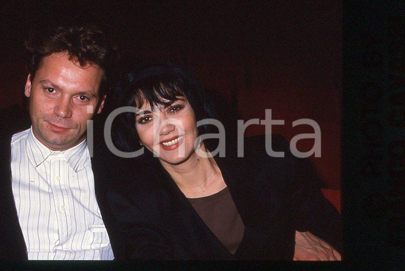 1985 ca ITALIA - MUSICA Marina FIORDALISO con il marito - 35 mm vintage slide 2 Diapositiva d'epoca, in formato 35 mm.CONDIZIONI: GOODE' severamente vietata la riproduzione. Tutti i diritti sono riservati.Nella diapositiva ICharta mette in vendita, sul negozio eBay e in esclusiva sul sito "icharta" il proprio archivio composto da numerose diapositive e negativi fotografici d'epoca, tutti originali e autentici, che attraversano la storia del costume italiano tra gli la fine degli anni Sessanta e Novanta.Si tratta di uno sguardo inedito sull'attualità , la politica, la vita quotidiana, il gossip e la cultura, che fotografa il cambiamento della nazione in quest'ultimo scorcio del XX secolo. Un'occasione unica per il mercato del collezionismo, che vede finalmente disponibile un archivio eccezionale per vastità , tematiche e condizioni, in un settore (il negativo fotografico e la diapositiva) di assoluta novità e dalle interessanti prospettive di investimento.  GOOD/buono   originale e autentica 1