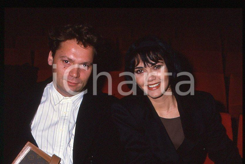 1985 ca ITALIA - MUSICA Marina FIORDALISO con il marito - 35 mm vintage slide Diapositiva d'epoca, in formato 35 mm.CONDIZIONI: GOODE' severamente vietata la riproduzione. Tutti i diritti sono riservati.Nella diapositiva ICharta mette in vendita, sul negozio eBay e in esclusiva sul sito "icharta" il proprio archivio composto da numerose diapositive e negativi fotografici d'epoca, tutti originali e autentici, che attraversano la storia del costume italiano tra gli la fine degli anni Sessanta e Novanta.Si tratta di uno sguardo inedito sull'attualità , la politica, la vita quotidiana, il gossip e la cultura, che fotografa il cambiamento della nazione in quest'ultimo scorcio del XX secolo. Un'occasione unica per il mercato del collezionismo, che vede finalmente disponibile un archivio eccezionale per vastità , tematiche e condizioni, in un settore (il negativo fotografico e la diapositiva) di assoluta novità e dalle interessanti prospettive di investimento.  GOOD/buono   originale e autentica 1