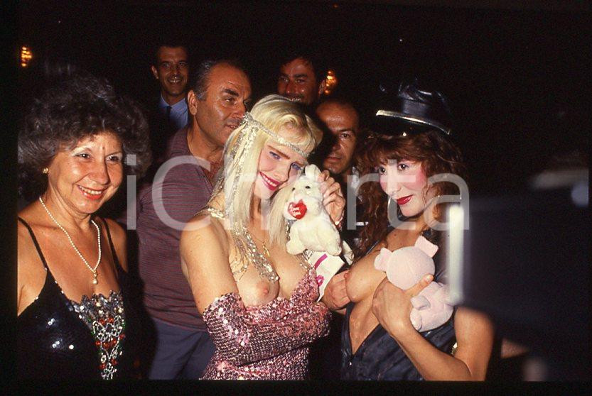 1980 ca CICCIOLINA Ilona STALLER - RAMBA Ileana CARISIO - 35 mm vintage slide Diapositiva d'epoca, in formato 35 mm.CONDIZIONI: GOODE' severamente vietata la riproduzione. Tutti i diritti sono riservati.Nella diapositiva ICharta mette in vendita, sul negozio eBay e in esclusiva sul sito "icharta" il proprio archivio composto da numerose diapositive e negativi fotografici d'epoca, tutti originali e autentici, che attraversano la storia del costume italiano tra gli la fine degli anni Sessanta e Novanta.Si tratta di uno sguardo inedito sull'attualità , la politica, la vita quotidiana, il gossip e la cultura, che fotografa il cambiamento della nazione in quest'ultimo scorcio del XX secolo. Un'occasione unica per il mercato del collezionismo, che vede finalmente disponibile un archivio eccezionale per vastità , tematiche e condizioni, in un settore (il negativo fotografico e la diapositiva) di assoluta novità e dalle interessanti prospettive di investimento.  GOOD/buono   originale e autentica 1