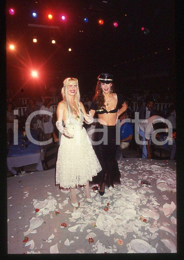 1980 ca CICCIOLINA Ilona STALLER - RAMBA Ileana CARISIO - 35 mm vintage slide 7 Diapositiva d'epoca, in formato 35 mm.CONDIZIONI: GOODE' severamente vietata la riproduzione. Tutti i diritti sono riservati.Nella diapositiva ICharta mette in vendita, sul negozio eBay e in esclusiva sul sito "icharta" il proprio archivio composto da numerose diapositive e negativi fotografici d'epoca, tutti originali e autentici, che attraversano la storia del costume italiano tra gli la fine degli anni Sessanta e Novanta.Si tratta di uno sguardo inedito sull'attualità , la politica, la vita quotidiana, il gossip e la cultura, che fotografa il cambiamento della nazione in quest'ultimo scorcio del XX secolo. Un'occasione unica per il mercato del collezionismo, che vede finalmente disponibile un archivio eccezionale per vastità , tematiche e condizioni, in un settore (il negativo fotografico e la diapositiva) di assoluta novità e dalle interessanti prospettive di investimento.  GOOD/buono   originale e autentica 1