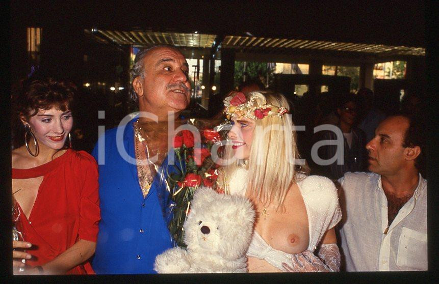 1980 ca CICCIOLINA Ilona STALLER Michalis LEFAKIS e RAMBA *35 mm vintage slide Diapositiva d'epoca, in formato 35 mm.CONDIZIONI: GOODE' severamente vietata la riproduzione. Tutti i diritti sono riservati.Nella diapositiva ICharta mette in vendita, sul negozio eBay e in esclusiva sul sito "icharta" il proprio archivio composto da numerose diapositive e negativi fotografici d'epoca, tutti originali e autentici, che attraversano la storia del costume italiano tra gli la fine degli anni Sessanta e Novanta.Si tratta di uno sguardo inedito sull'attualità , la politica, la vita quotidiana, il gossip e la cultura, che fotografa il cambiamento della nazione in quest'ultimo scorcio del XX secolo. Un'occasione unica per il mercato del collezionismo, che vede finalmente disponibile un archivio eccezionale per vastità , tematiche e condizioni, in un settore (il negativo fotografico e la diapositiva) di assoluta novità e dalle interessanti prospettive di investimento.  GOOD/buono   originale e autentica 1