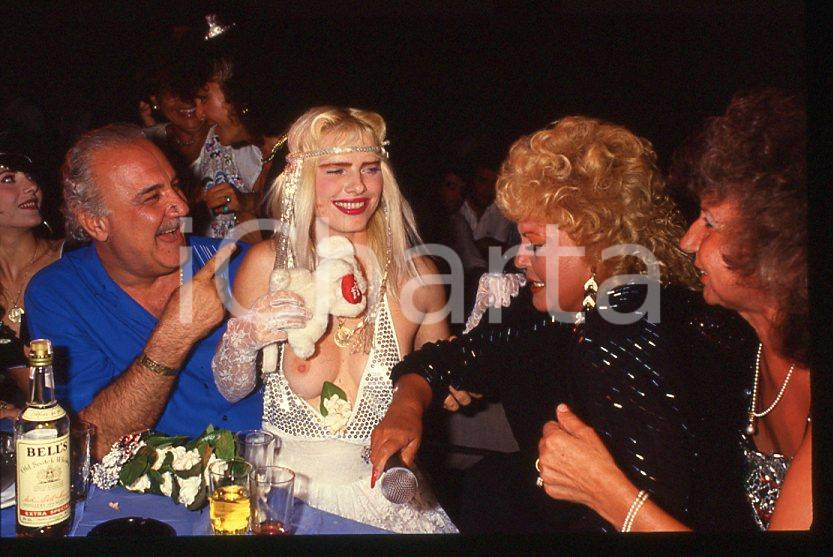 1980 ca CICCIOLINA Ilona STALLER Michalis LEFAKIS *35 mm vintage slide 7 Diapositiva d'epoca, in formato 35 mm.CONDIZIONI: GOODE' severamente vietata la riproduzione. Tutti i diritti sono riservati.Nella diapositiva ICharta mette in vendita, sul negozio eBay e in esclusiva sul sito "icharta" il proprio archivio composto da numerose diapositive e negativi fotografici d'epoca, tutti originali e autentici, che attraversano la storia del costume italiano tra gli la fine degli anni Sessanta e Novanta.Si tratta di uno sguardo inedito sull'attualità , la politica, la vita quotidiana, il gossip e la cultura, che fotografa il cambiamento della nazione in quest'ultimo scorcio del XX secolo. Un'occasione unica per il mercato del collezionismo, che vede finalmente disponibile un archivio eccezionale per vastità , tematiche e condizioni, in un settore (il negativo fotografico e la diapositiva) di assoluta novità e dalle interessanti prospettive di investimento.  GOOD/buono   originale e autentica 1