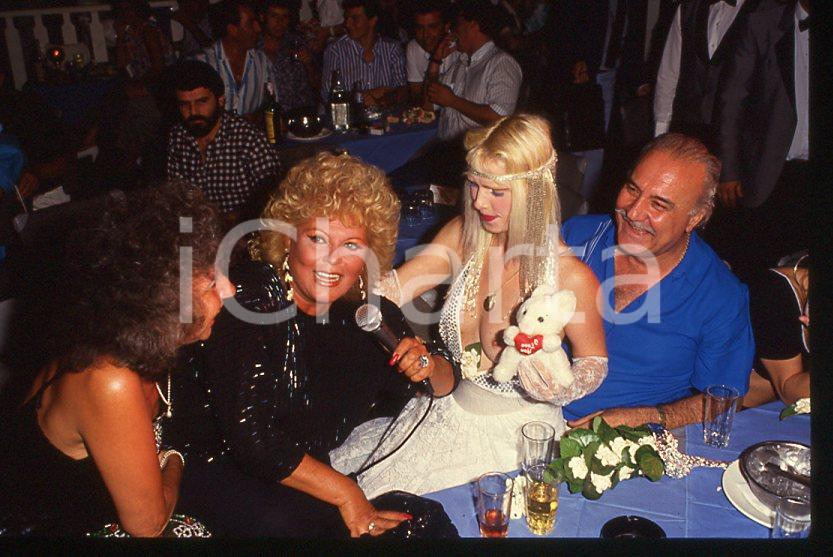 1980 ca CICCIOLINA Ilona STALLER Michalis LEFAKIS *35 mm vintage slide 9 Diapositiva d'epoca, in formato 35 mm.CONDIZIONI: GOODE' severamente vietata la riproduzione. Tutti i diritti sono riservati.Nella diapositiva ICharta mette in vendita, sul negozio eBay e in esclusiva sul sito "icharta" il proprio archivio composto da numerose diapositive e negativi fotografici d'epoca, tutti originali e autentici, che attraversano la storia del costume italiano tra gli la fine degli anni Sessanta e Novanta.Si tratta di uno sguardo inedito sull'attualità , la politica, la vita quotidiana, il gossip e la cultura, che fotografa il cambiamento della nazione in quest'ultimo scorcio del XX secolo. Un'occasione unica per il mercato del collezionismo, che vede finalmente disponibile un archivio eccezionale per vastità , tematiche e condizioni, in un settore (il negativo fotografico e la diapositiva) di assoluta novità e dalle interessanti prospettive di investimento.  GOOD/buono   originale e autentica 1