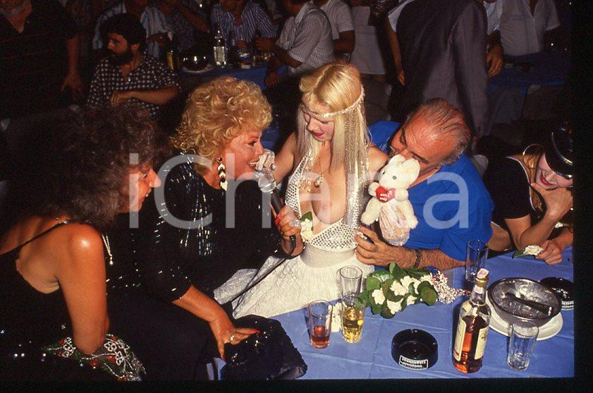 1980 ca CICCIOLINA Ilona STALLER Michalis LEFAKIS *35 mm vintage slide 10 Diapositiva d'epoca, in formato 35 mm.CONDIZIONI: GOODE' severamente vietata la riproduzione. Tutti i diritti sono riservati.Nella diapositiva ICharta mette in vendita, sul negozio eBay e in esclusiva sul sito "icharta" il proprio archivio composto da numerose diapositive e negativi fotografici d'epoca, tutti originali e autentici, che attraversano la storia del costume italiano tra gli la fine degli anni Sessanta e Novanta.Si tratta di uno sguardo inedito sull'attualità , la politica, la vita quotidiana, il gossip e la cultura, che fotografa il cambiamento della nazione in quest'ultimo scorcio del XX secolo. Un'occasione unica per il mercato del collezionismo, che vede finalmente disponibile un archivio eccezionale per vastità , tematiche e condizioni, in un settore (il negativo fotografico e la diapositiva) di assoluta novità e dalle interessanti prospettive di investimento.  GOOD/buono   originale e autentica 1