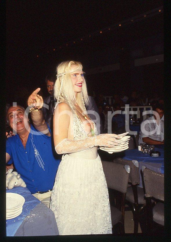 1980 ca CICCIOLINA Ilona STALLER Michalis LEFAKIS *35 mm vintage slide 11 Diapositiva d'epoca, in formato 35 mm.CONDIZIONI: GOODE' severamente vietata la riproduzione. Tutti i diritti sono riservati.Nella diapositiva ICharta mette in vendita, sul negozio eBay e in esclusiva sul sito "icharta" il proprio archivio composto da numerose diapositive e negativi fotografici d'epoca, tutti originali e autentici, che attraversano la storia del costume italiano tra gli la fine degli anni Sessanta e Novanta.Si tratta di uno sguardo inedito sull'attualità , la politica, la vita quotidiana, il gossip e la cultura, che fotografa il cambiamento della nazione in quest'ultimo scorcio del XX secolo. Un'occasione unica per il mercato del collezionismo, che vede finalmente disponibile un archivio eccezionale per vastità , tematiche e condizioni, in un settore (il negativo fotografico e la diapositiva) di assoluta novità e dalle interessanti prospettive di investimento.  GOOD/buono   originale e autentica 1