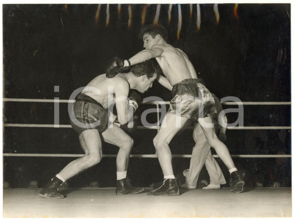 1955 LONDON BOXE European Flyweight Title - Dai DOWER vs Nazzareno GIANNELLI Fotografia d'epoca, con didascalia coeva al verso, stampata su carta sottile.CONDIZIONI: FAIR (increspatura al margine superiore, piegature angolari al margine destro, graffi al margine sinistro, lievi difetti di stampa e brunitura al margine inferiore)FORMATO: 20x15 cm     originale e autentica 1