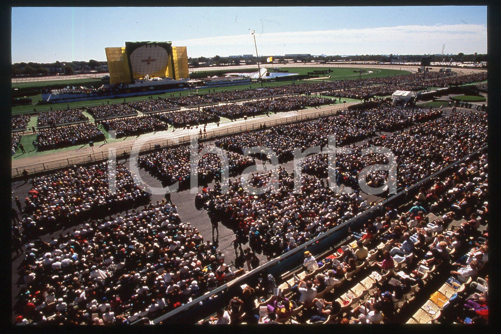 35mm vintage slide* 1995 BROOKLYN Aqueduct Racetrack - People waiting for Pope 1  Diapositiva d'epoca, in formato 35 mm.CONDIZIONI: GOODE' severamente vietata la riproduzione. Tutti i diritti sono riservati.Nella diapositiva ICharta mette in vendita, sul negozio eBay e in esclusiva sul sito "icharta" il proprio archivio composto da numerose diapositive e negativi fotografici d'epoca, tutti originali e autentici, che attraversano la storia del costume italiano tra gli la fine degli anni Sessanta e Novanta.Si tratta di uno sguardo inedito sull'attualit&agrave;, la politica, la vita quotidiana, il gossip e la cultura, che fotografa il cambiamento della nazione in quest'ultimo scorcio del XX secolo. Un'occasione unica per il mercato del collezionismo, che vede finalmente disponibile un archivio eccezionale per vastit&agrave;, tematiche e condizioni, in un settore (il negativo fotografico e la diapositiva) di assoluta novit&agrave; e dalle interessanti prospettive di investimento.   FAIR/discreto   originale e autentica 1