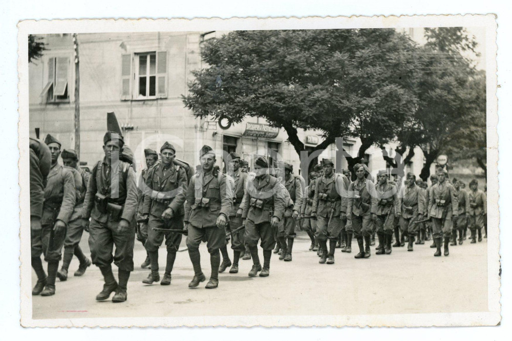 1935 ca MASONE Militari di ritorno da esercitazione di tiro - Foto 14x9 cm Fotografia d'epoca in formato cartolina postale, con didascalie al recto. CONDIZIONI:POOR/danneggiato Piegature e segno di inchiostro all'angolo inferiore sinistro, piegatura al margine destro, residui di incollatura al versoFORMATO: 14x9 cm originale e autentica 1