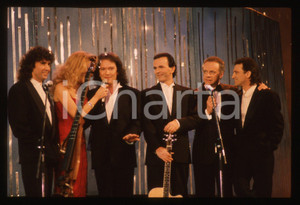 35mm vintage slide* 1990 Festival SANREMO POOH Gabriella CARLUCCI Johnny DORELLI   Diapositiva d'epoca, in formato 35 mm.Nella diapositiva i componenti del gruppo musicale POOH (Roby Facchinetti, Dodi Battaglia, Stefano D'Orazio e Red Canzian) con Gabriella Carlucci e Johnny Dorelli sul palcoscenico del Festival di Sanremo del 1990. CONDIZIONI: GOODE' severamente vietata la riproduzione. Tutti i diritti sono riservati. ICharta mette in vendita, sul negozio eBay e in esclusiva sul sito "icharta" il proprio archivio composto da numerose diapositive e negativi fotografici d'epoca, tutti originali e autentici, che attraversano la storia del costume italiano tra gli la fine degli anni Sessanta e Novanta.Si tratta di uno sguardo inedito sull'attualit&agrave;, la politica, la vita quotidiana, il gossip e la cultura, che fotografa il cambiamento della nazione in quest'ultimo scorcio del XX secolo. Un'occasione unica per il mercato del collezionismo, che vede finalmente disponibile un archivio eccezionale per vastit&agrave;, tematiche e condizioni, in un settore (il negativo fotografico e la diapositiva) di assoluta novit&agrave; e dalle interessanti prospettive di investimento.  originale e autentica 1