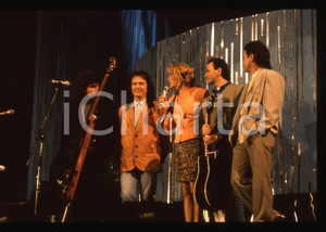 35mm vintage slide* 1990 Festival di SANREMO -  POOH con Gabriella CARLUCCI   Diapositiva d'epoca, in formato 35 mm.Nella diapositiva i componenti del gruppo musicale POOH: Roby Facchinetti, Dodi Battaglia, Stefano D'Orazio e Red Canzian con la presentatrice Gabriella Carlucci al Festival di Sanremo del 1990. CONDIZIONI: GOODE' severamente vietata la riproduzione. Tutti i diritti sono riservati. ICharta mette in vendita, sul negozio eBay e in esclusiva sul sito "icharta" il proprio archivio composto da numerose diapositive e negativi fotografici d'epoca, tutti originali e autentici, che attraversano la storia del costume italiano tra gli la fine degli anni Sessanta e Novanta.Si tratta di uno sguardo inedito sull'attualit&agrave;, la politica, la vita quotidiana, il gossip e la cultura, che fotografa il cambiamento della nazione in quest'ultimo scorcio del XX secolo. Un'occasione unica per il mercato del collezionismo, che vede finalmente disponibile un archivio eccezionale per vastit&agrave;, tematiche e condizioni, in un settore (il negativo fotografico e la diapositiva) di assoluta novit&agrave; e dalle interessanti prospettive di investimento.  originale e autentica 1