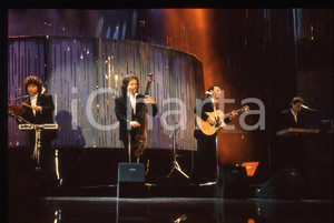 35mm vintage slide* 1990 Festival di SANREMO - POOH cantano "UOMINI SOLI" (2)   Diapositiva d'epoca, in formato 35 mm.Nella diapositiva i componenti del gruppo musicale POOH: Roby Facchinetti, Dodi Battaglia, Stefano D'Orazio e Red Canzian durante il Festival di Sanremo del 1990. CONDIZIONI: GOODE' severamente vietata la riproduzione. Tutti i diritti sono riservati. ICharta mette in vendita, sul negozio eBay e in esclusiva sul sito "icharta" il proprio archivio composto da numerose diapositive e negativi fotografici d'epoca, tutti originali e autentici, che attraversano la storia del costume italiano tra gli la fine degli anni Sessanta e Novanta.Si tratta di uno sguardo inedito sull'attualit&agrave;, la politica, la vita quotidiana, il gossip e la cultura, che fotografa il cambiamento della nazione in quest'ultimo scorcio del XX secolo. Un'occasione unica per il mercato del collezionismo, che vede finalmente disponibile un archivio eccezionale per vastit&agrave;, tematiche e condizioni, in un settore (il negativo fotografico e la diapositiva) di assoluta novit&agrave; e dalle interessanti prospettive di investimento.  originale e autentica 1