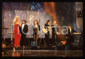 35mm vintage slide* 1990 Festival SANREMO POOH Johnny DORELLI Gabriella CARLUCCI   Diapositiva d'epoca, in formato 35 mm.Nella diapositiva i componenti del gruppo musicale POOH (Roby Facchinetti, Dodi Battaglia, Stefano D'Orazio e Red Canzian) con Gabriella Carlucci e Johnny Dorelli sul palcoscenico del Festival di Sanremo del 1990. CONDIZIONI: GOODE' severamente vietata la riproduzione. Tutti i diritti sono riservati. ICharta mette in vendita, sul negozio eBay e in esclusiva sul sito "icharta" il proprio archivio composto da numerose diapositive e negativi fotografici d'epoca, tutti originali e autentici, che attraversano la storia del costume italiano tra gli la fine degli anni Sessanta e Novanta.Si tratta di uno sguardo inedito sull'attualit&agrave;, la politica, la vita quotidiana, il gossip e la cultura, che fotografa il cambiamento della nazione in quest'ultimo scorcio del XX secolo. Un'occasione unica per il mercato del collezionismo, che vede finalmente disponibile un archivio eccezionale per vastit&agrave;, tematiche e condizioni, in un settore (il negativo fotografico e la diapositiva) di assoluta novit&agrave; e dalle interessanti prospettive di investimento.  originale e autentica 1