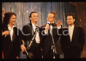 35mm vintage slide*1990 Festival SANREMO POOH Johnny DORELLI Gabriella CARLUCCI*   Diapositiva d'epoca, in formato 35 mm.Nella diapositiva i componenti del gruppo musicale POOH (Roby Facchinetti, Dodi Battaglia e Red Canzian) con Gabriella Carlucci e Johnny Dorelli sul palcoscenico del Festival di Sanremo del 1990. CONDIZIONI: GOODE' severamente vietata la riproduzione. Tutti i diritti sono riservati. ICharta mette in vendita, sul negozio eBay e in esclusiva sul sito "icharta" il proprio archivio composto da numerose diapositive e negativi fotografici d'epoca, tutti originali e autentici, che attraversano la storia del costume italiano tra gli la fine degli anni Sessanta e Novanta.Si tratta di uno sguardo inedito sull'attualit&agrave;, la politica, la vita quotidiana, il gossip e la cultura, che fotografa il cambiamento della nazione in quest'ultimo scorcio del XX secolo. Un'occasione unica per il mercato del collezionismo, che vede finalmente disponibile un archivio eccezionale per vastit&agrave;, tematiche e condizioni, in un settore (il negativo fotografico e la diapositiva) di assoluta novit&agrave; e dalle interessanti prospettive di investimento.  originale e autentica 1