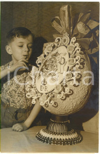 1957 PARIS - Child looks at an EASTER EGG with the ROYAL COAT OF ARMS of UK