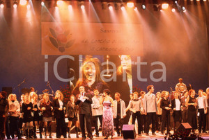 35mm vintage slide* 1999 GRANDE MEETING SANREMO Ettore ANDENNA e MARIADELE (1)  Diapositiva d'epoca, in formato 35 mm.CONDIZIONI: GOODNella diapositiva compaiono i componenti del guppo vocale Emmanuel.E' severamente vietata la riproduzione. Tutti i diritti sono riservati.Nella diapositiva ICharta mette in vendita, sul negozio eBay e in esclusiva sul sito "icharta" il proprio archivio composto da numerose diapositive e negativi fotografici d'epoca, tutti originali e autentici, che attraversano la storia del costume italiano tra gli la fine degli anni Sessanta e Novanta.Si tratta di uno sguardo inedito sull'attualit&agrave;, la politica, la vita quotidiana, il gossip e la cultura, che fotografa il cambiamento della nazione in quest'ultimo scorcio del XX secolo. Un'occasione unica per il mercato del collezionismo, che vede finalmente disponibile un archivio eccezionale per vastit&agrave;, tematiche e condizioni, in un settore (il negativo fotografico e la diapositiva) di assoluta novit&agrave; e dalle interessanti prospettive di investimento. GOOD/buono   originale e autentica 1