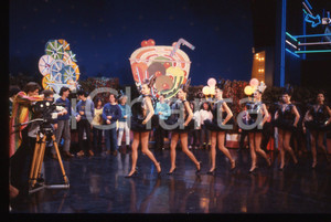 35mm vintage slide* 1985ca DRIVE IN Italia 1 EZIO GREGGIO dirige ragazze BOMBERS   Diapositiva d'epoca, in formato 35 mm. CONDIZIONI: GOODTutti i diritti riservati.E' severamente vietata la riproduzione. ICharta mette in vendita, sul negozio eBay e in esclusiva sul sito "icharta" il proprio archivio composto da numerose diapositive e negativi fotografici d'epoca, tutti originali e autentici, che attraversano la storia del costume italiano tra gli la fine degli anni Sessanta e Novanta.Si tratta di uno sguardo inedito sull'attualità, la politica, la vita quotidiana, il gossip e la cultura, che fotografa il cambiamento della nazione in quest'ultimo scorcio del XX secolo. Un'occasione unica per il mercato del collezionismo, che vede finalmente disponibile un archivio eccezionale per vastità, tematiche e condizioni, in un settore (il negativo fotografico e la diapositiva) di assoluta novità e dalle interessanti prospettive di investimento.  originale e autentica 1
