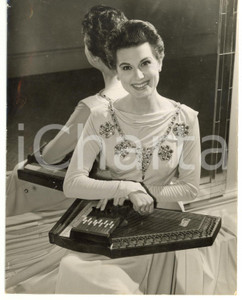 1956 LONDON Doretta MORROW playing the zither *Photo 15x20 Fotografia d'epoca, con didascalia coeva al verso. CONDIZIONI: FAIR (piccole piegature; strappo millimetrico al margine sinistro)FORMATO: 15x20 cm    originale e autentica 1