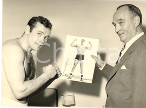 1959 BOXE Ritratto pugile Ingemar JOHANSSON con la foto di un avversario - Foto Fotografia d'epoca con didascalia coeva.  CONDIZIONI: FAIR (piccola piegatura angolare e lievi sovraimpressioni) FORMATO: 18x13 cm    originale e autentica 1