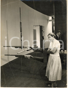 Fotografia d epoca originale 1957 TRIENNALE DI MILANO Visitatrice osserva armi Fabrique Nationale de Herstal 1