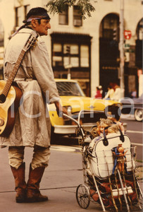 1975 ca USA Homeless with guitar and a trolley full of dolls - Photo 20x30 cm Fotografia d'epoca. FAIR/discreto Residui di incollatura al verso Formato: 20x30 cm originale e autentica 1