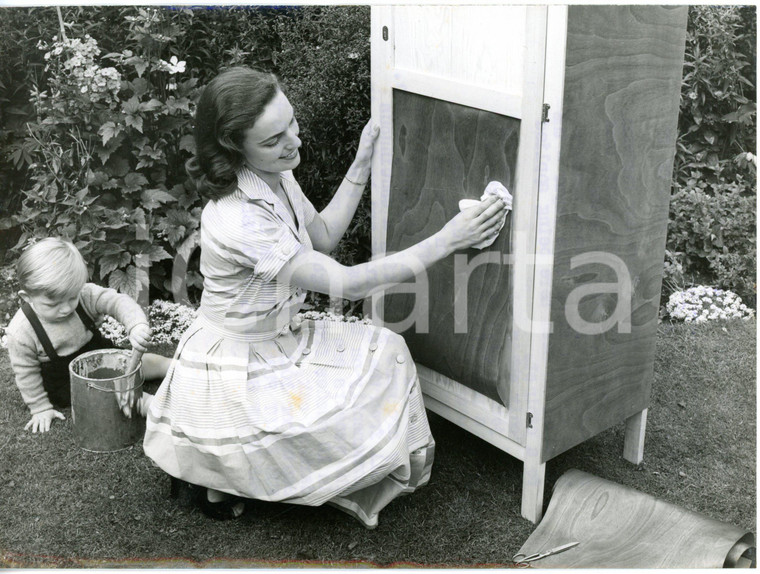 1954 LONDON - Young girl covering old forniture with sheets of real wood *Photo