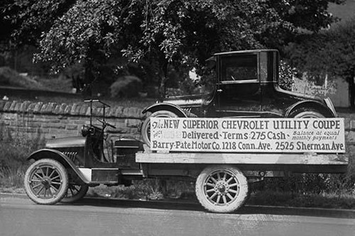 Truck carries a Chevrolet Coupe Advertisement with an actual vehicle on board