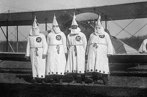 Four Hooded White Sheeted Ku Klux Klan Member pose in Robes & Hoods in front of Airplane