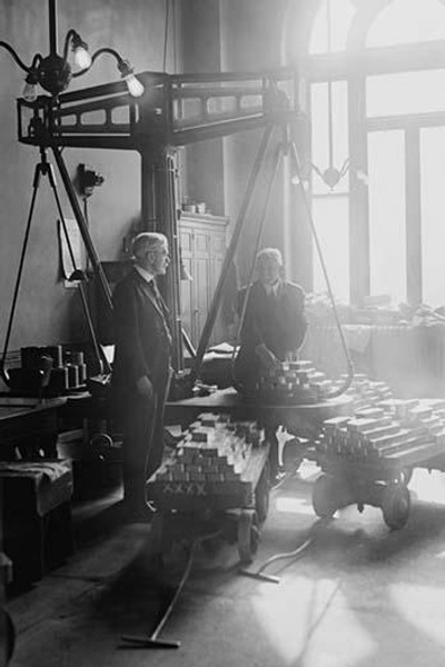 Two suited men weigh bars of gold on scales at the US Mint