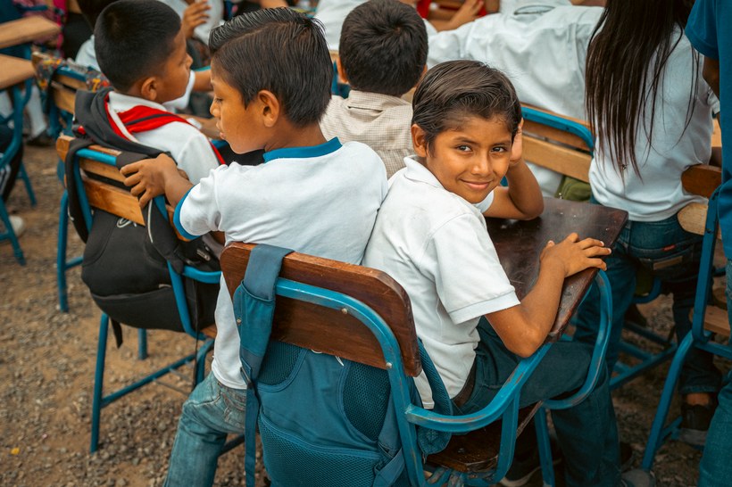Students seated at desks in a classroom funded through Denik
