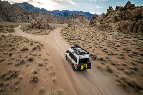 Photo of van with Starlink on roof driving down a remote dirt road, coming to a fork in the road with mountains in the background