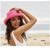 A woman on the beach wearing a pink Scala 2" brim Bari sun hat sold by Island Pursuit offering free shipping over $100