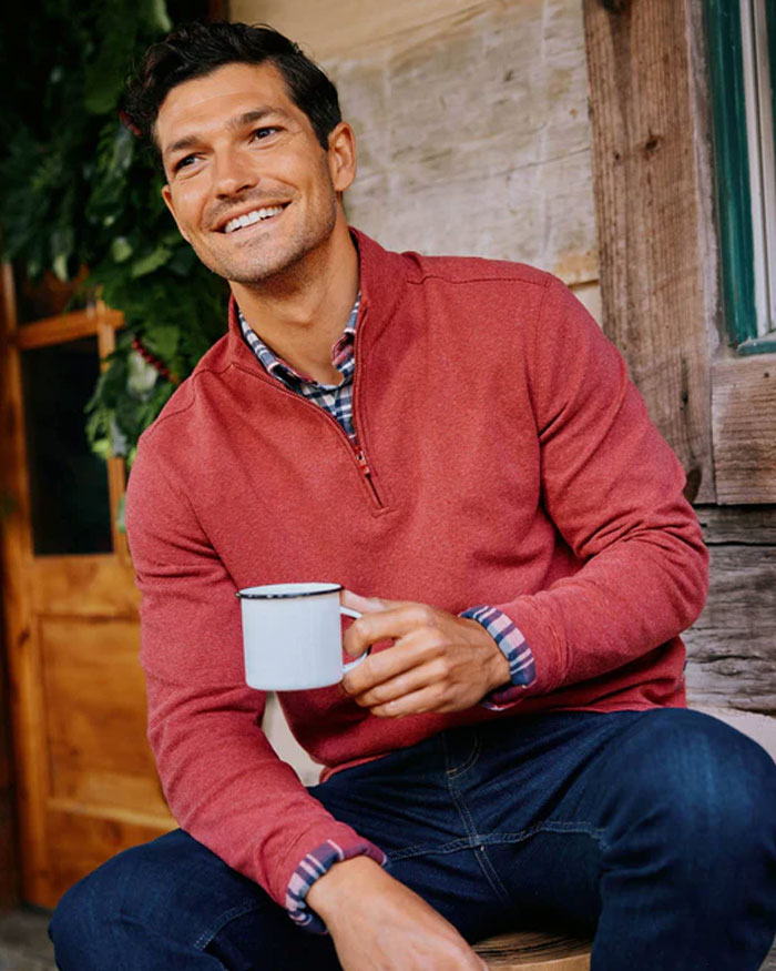 a man wearing red sweater holding a coffee mug.