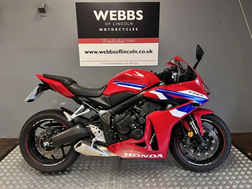 Honda CBR 650-R motorcycle at Webbs Motorcycles with red, blue, and white color scheme, displayed indoors on a metal platform.