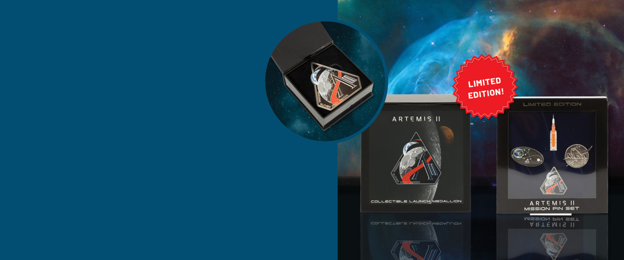 Artemis II limited edition pin set and launch medallion in black boxes on a blue space background.
