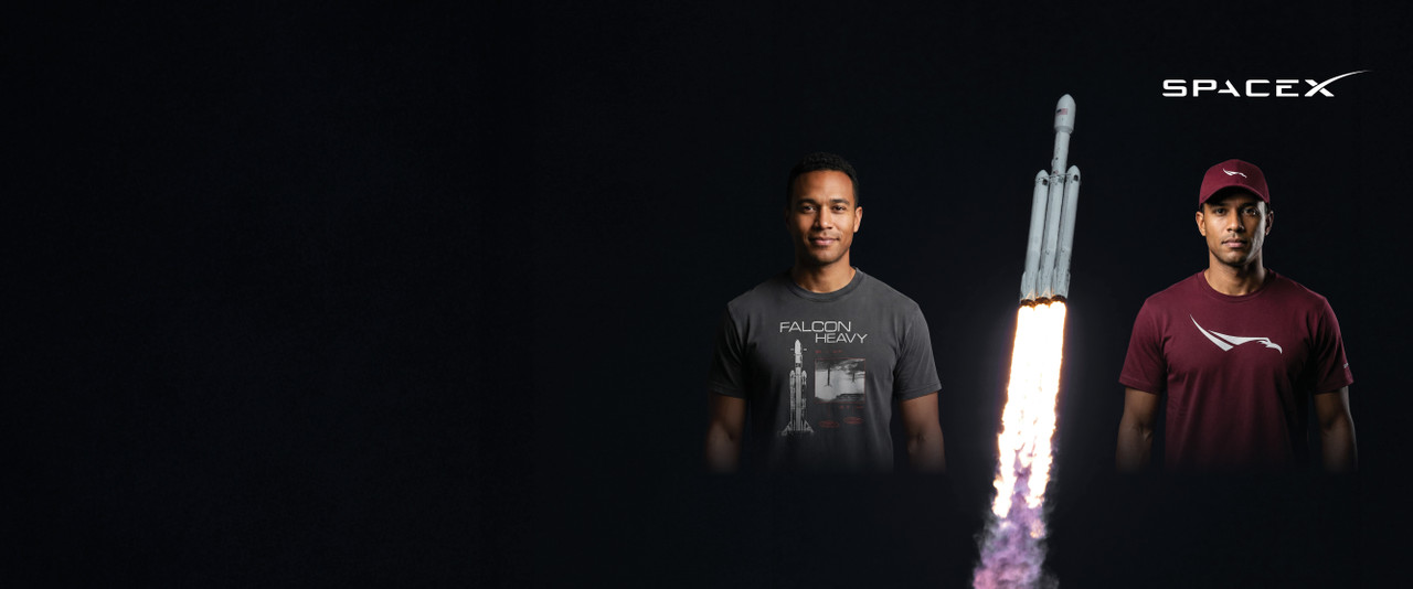 Falcon Heavy rocket surrounded by two men wearing SpaceX Falcon tees and a hat in black and maroon.