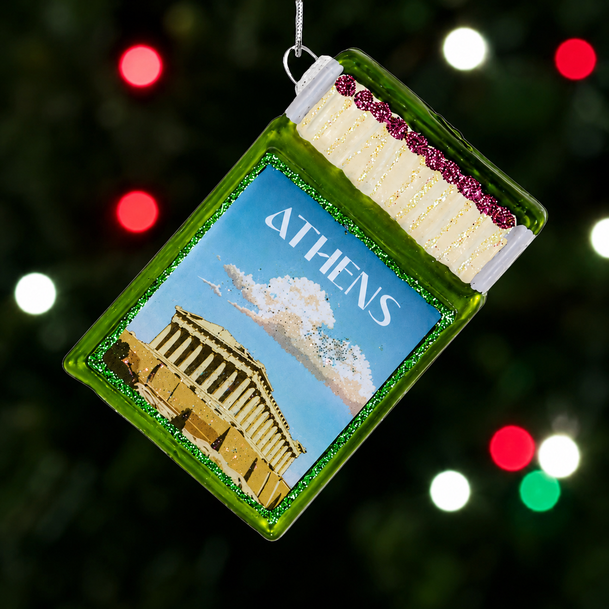 Glass Athens souvenir matchbox ornament with green frame and landmark scene.
Greek travel Christmas ornament with Athens text and glittered match details.